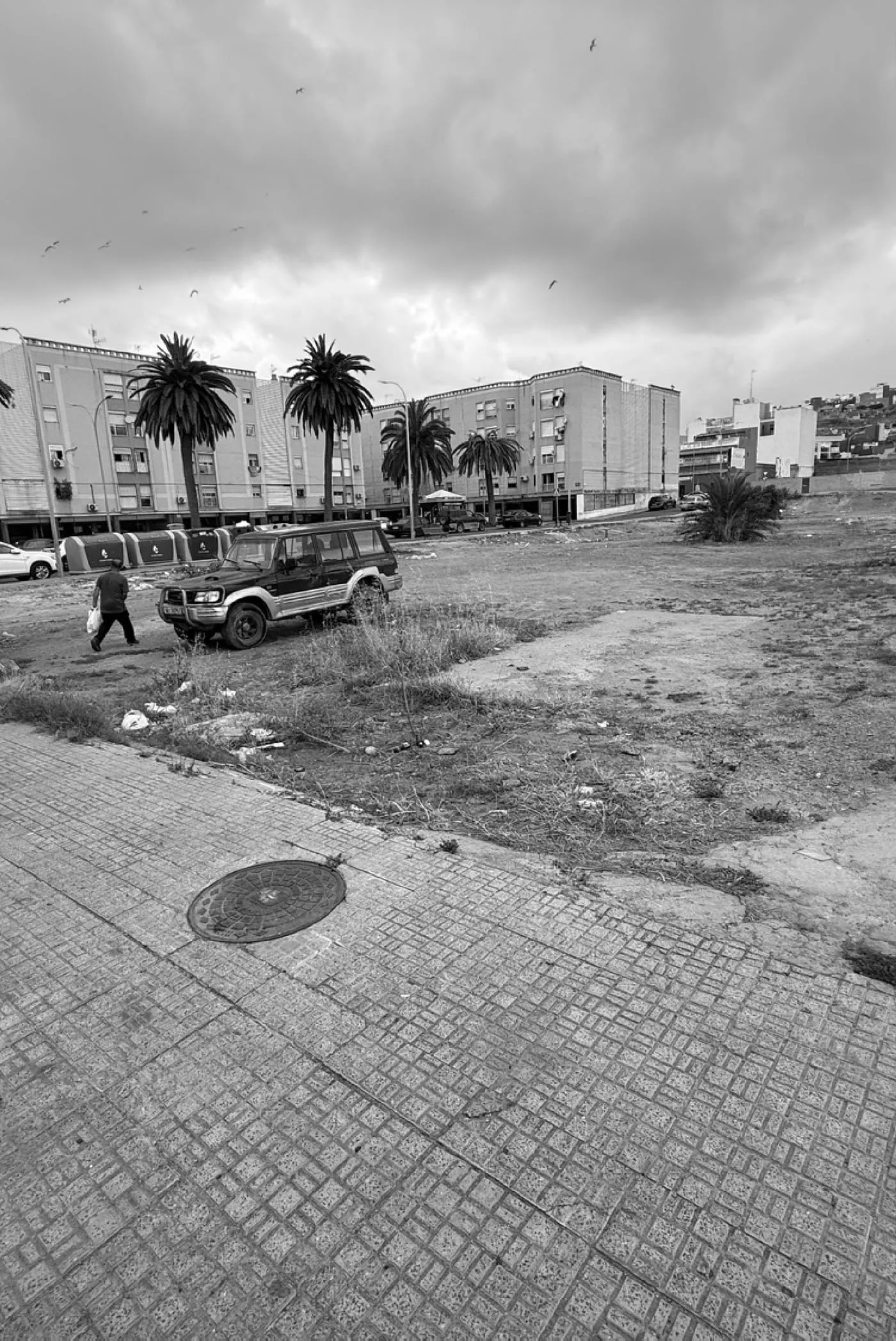Undeveloped plot on the Ctra. de Hidum in Melilla, with apartment blocks and palm trees behind